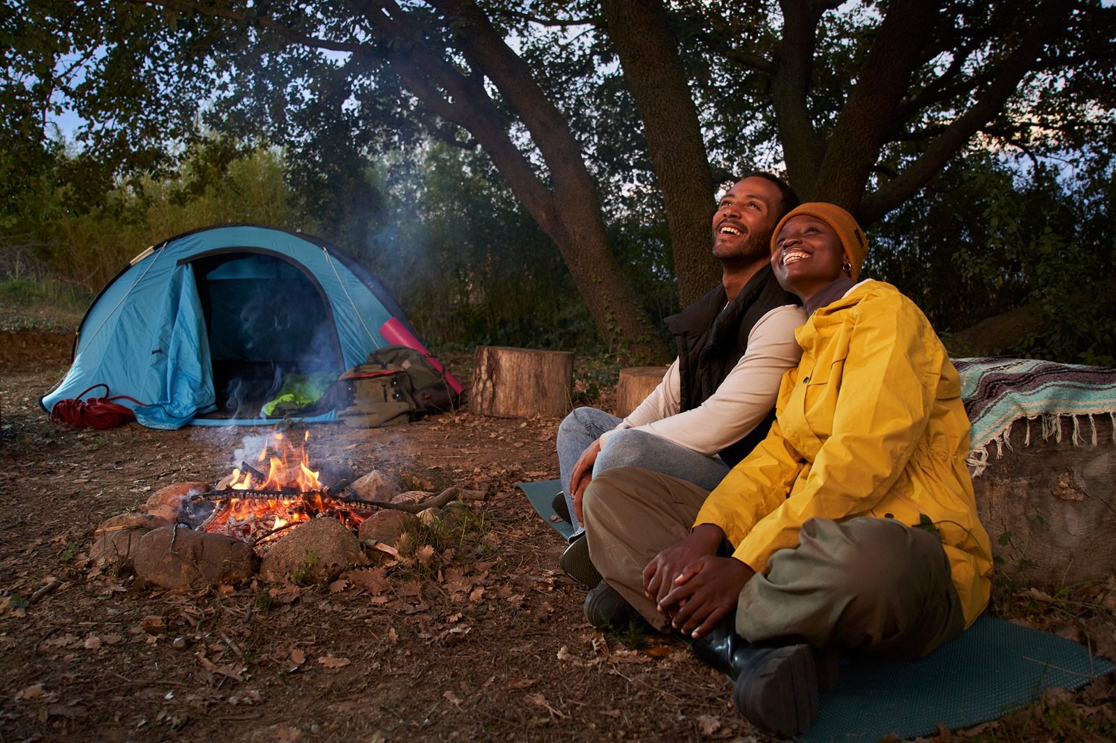 Two guests sharing a campfire beside their tent as the light goes