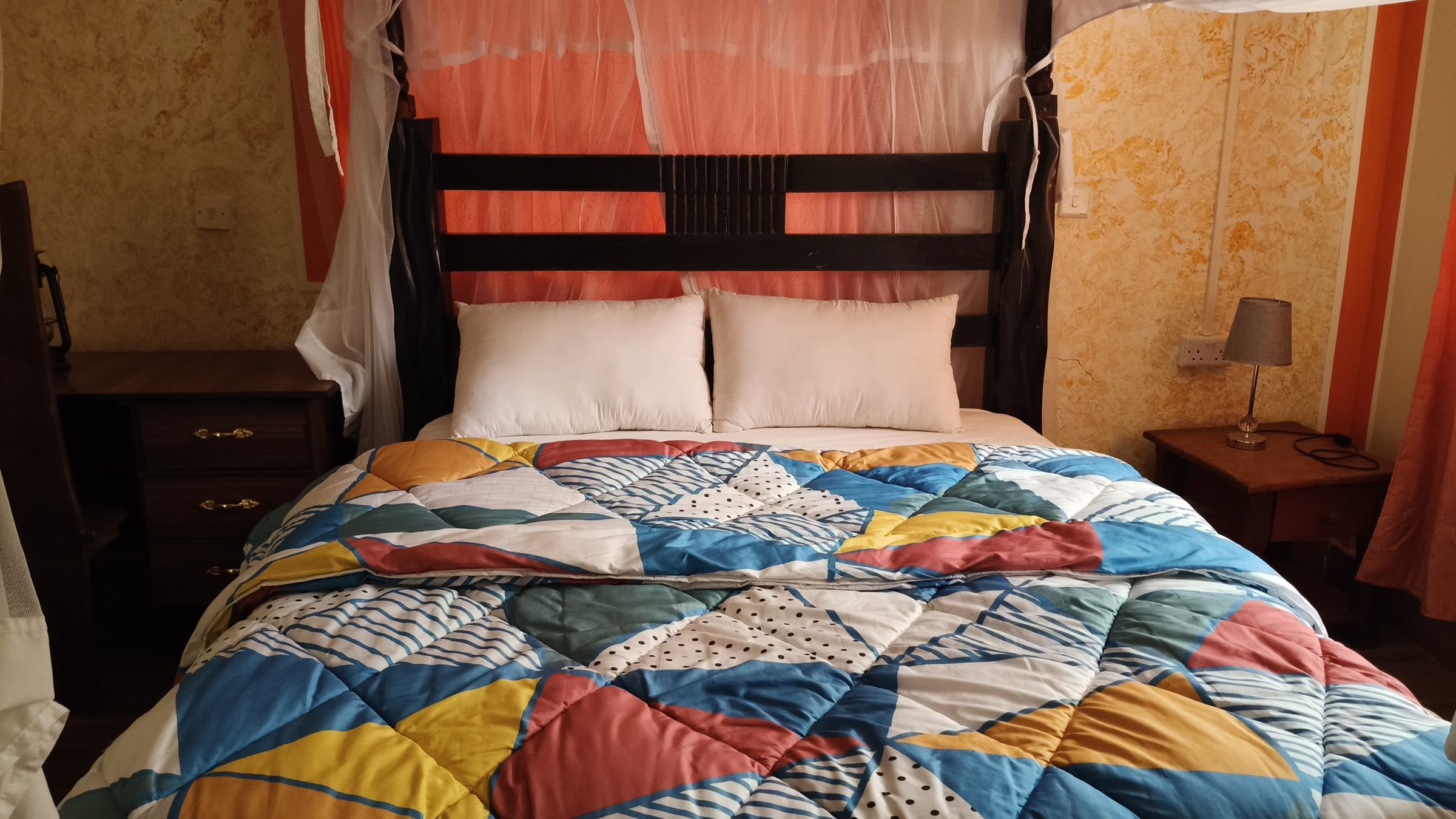 Guest house double room with a carved headboard and bright quilt
